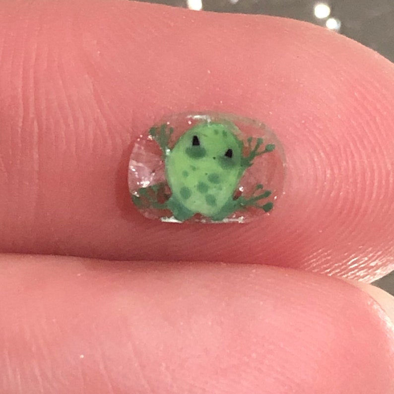 Ann’s tiny bright-green frog murrini resting on a fingertip